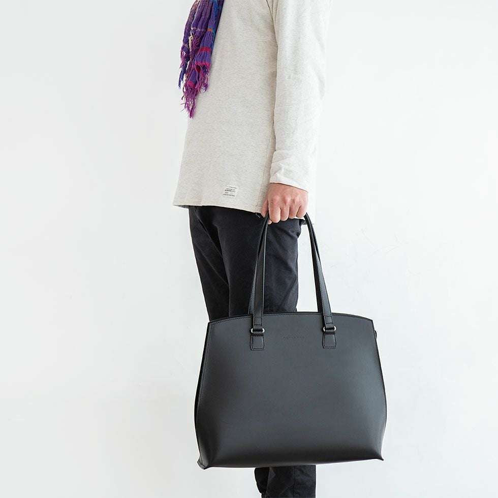 リスシオレザートートを手さげスタイルで持つ男性モデル画像