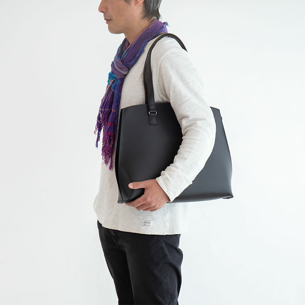 リスシオレザートートを肩掛けスタイルで持つ男性モデル